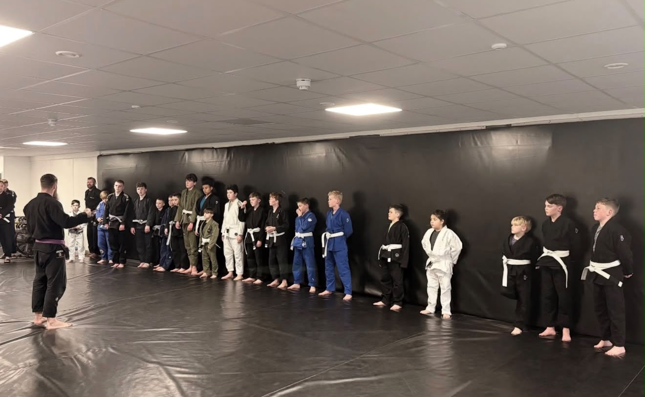 Junior class lined up along the mat wall before training